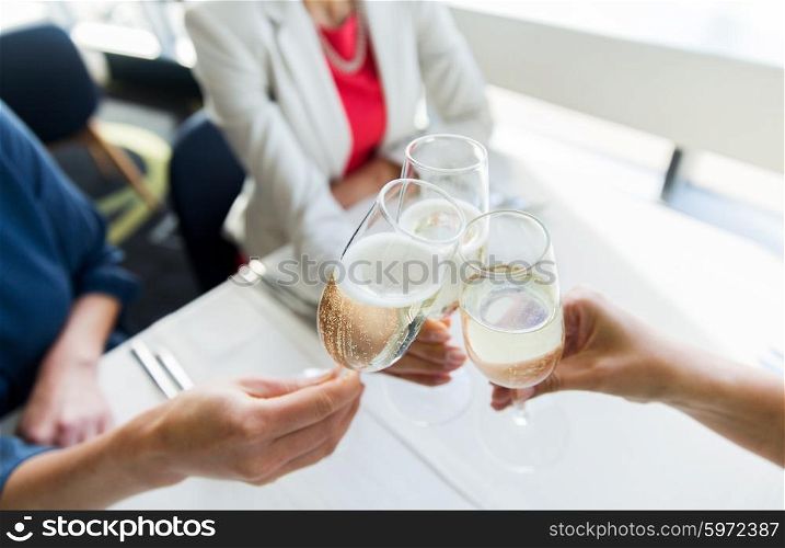 people, holidays, celebration and lifestyle concept - close up of women clinking champagne glasses at restaurant