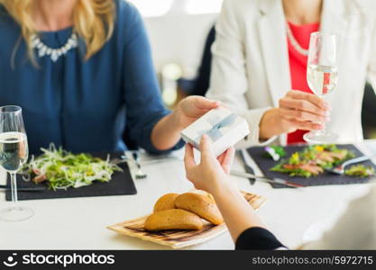 people, holidays, celebration and lifestyle concept - close up of women giving birthday present at restaurant