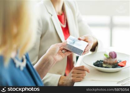 people, holidays, celebration and lifestyle concept - close up of women giving birthday present at restaurant