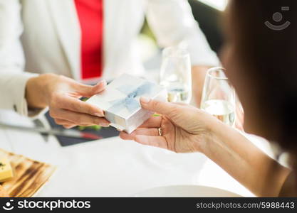 people, holidays, celebration and lifestyle concept - close up of women giving birthday present at restaurant