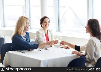 people, holidays, celebration and lifestyle concept - happy women drinking champagne and clinking glasses at restaurant