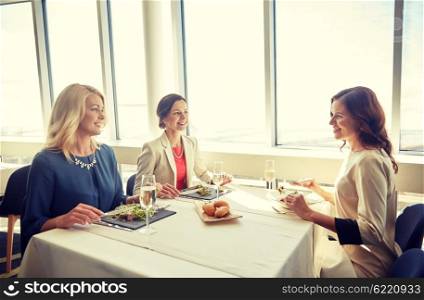 people, holidays, celebration and lifestyle concept - happy women eating and drinking champagne at restaurant