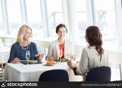 people, holidays, celebration and lifestyle concept - happy women eating and drinking champagne at restaurant