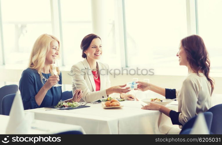 people, holidays, celebration and lifestyle concept - happy women giving birthday present at restaurant