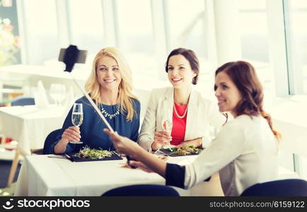 people, holidays, celebration and lifestyle concept - happy women with smartphone selfie stick taking picture at restaurant