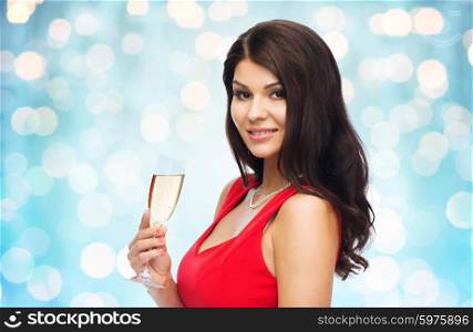 people, holidays, christmas and celebration concept - beautiful sexy woman in red dress with champagne glass over blue lights background