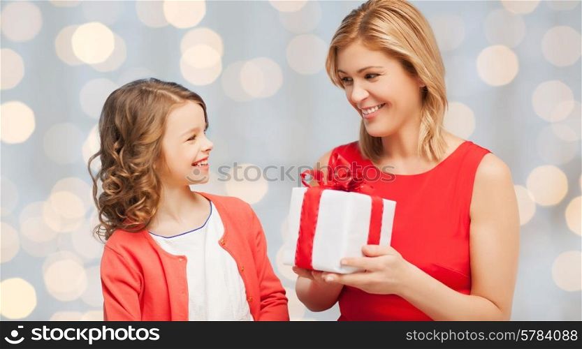 people, holidays, christmas and family concept - happy mother and daughter giving and receiving gift box over holiday lights background