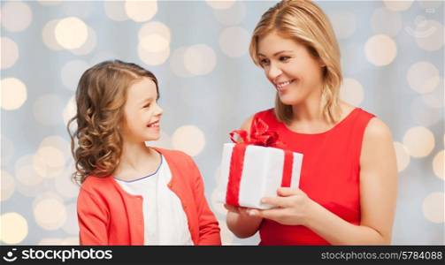 people, holidays, christmas and family concept - happy mother and daughter giving and receiving gift box over holiday lights background
