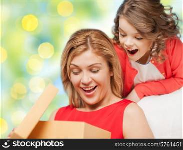 people, holidays, christmas and family concept - happy mother and daughter opening gift box over green lights background
