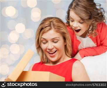 people, holidays, christmas and family concept - happy mother and daughter opening gift box over holiday lights background