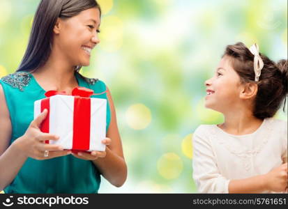 people, holidays, christmas and family concept - happy mother and daughter with gift box over green lights background