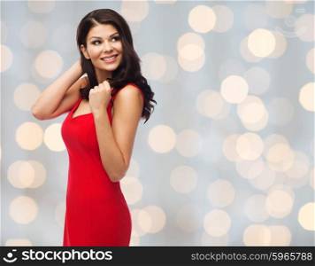 people, holidays, christmas and fashion concept - beautiful sexy woman in red dress over holidays lights background