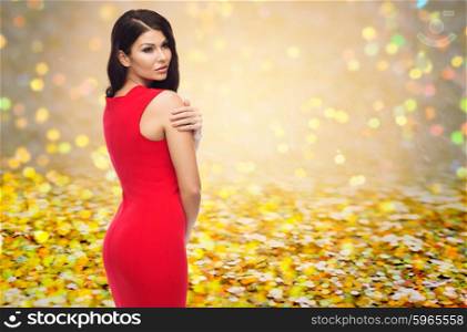 people, holidays, christmas and glamour concept - beautiful sexy woman in red dress over golden glitter or yellow lights background