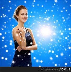 people, holidays, christmas and people concept - smiling woman in evening dress over blue snowy background