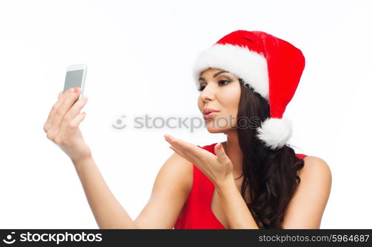 people, holidays, christmas and technology concept - beautiful sexy woman in red santa hat taking selfie picture by smartphone and sending blow kiss to camera