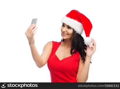 people, holidays, christmas and technology concept - beautiful sexy woman in red santa hat taking selfie picture by smartphone