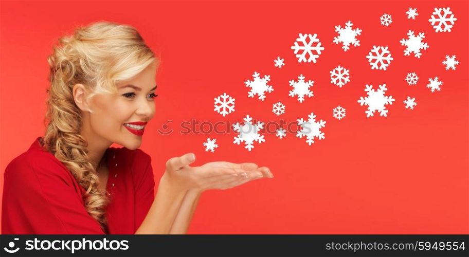 people, holidays, christmas and winter concept - lovely woman in red clothes sending snowflakes from on palms of her hands over red background