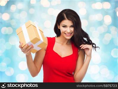 people, holidays, christmas, birthday and celebration concept - beautiful sexy woman in red dress with gift box over blue lights background