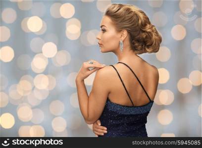 people, holidays, christmas, jewelry and glamour concept - beautiful woman with diamond earring over lights background