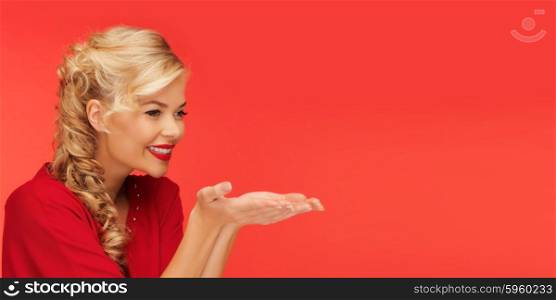 people, holidays, christmas, valentines day and advertisement concept - lovely woman in red clothes holding something on palms of her hands over red background