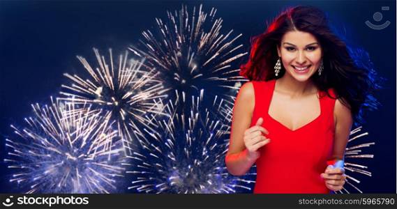people, holidays, disco, nightlife and leisure concept - beautiful sexy woman in red dress dancing at party over firework in night sky background
