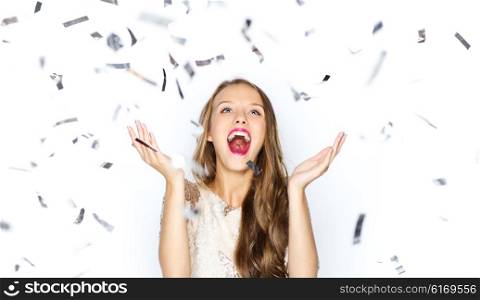 people, holidays, emotion and glamour concept - happy young woman or teen girl in fancy dress with sequins and confetti at party