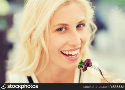 people, holidays, food and leisure concept - happy woman with fork eating squid for dinner at restaurant terrace