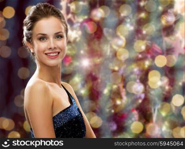 people, holidays, jewelry and glamour concept - happy beautiful woman wearing pearl earrings over christmas lights background