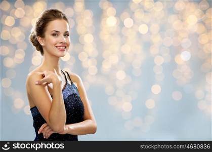 people, holidays, jewelry and luxury concept - smiling woman in evening dress and pearl earring over lights background