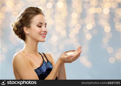 people, holidays, jewelry and luxury concept - smiling woman in evening dress and diamond earrings over lights background