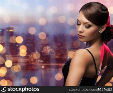 people, holidays, jewelry and luxury concept - woman face with diamond earring over night singapore city and lights background