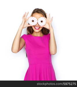 people, holidays, junk food and fast food concept - happy young woman or teen girl in pink dress having fun and looking through donuts