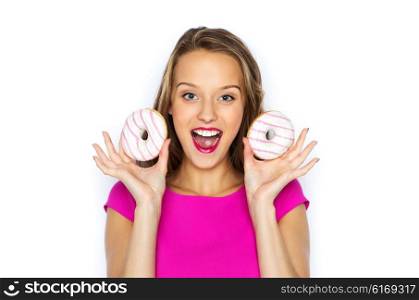 people, holidays, junk food and fast food concept - happy young woman or teen girl in pink dress with donuts