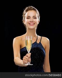 people, holidays, luxury and celebration concept - smiling woman holding glass of sparkling wine over black background