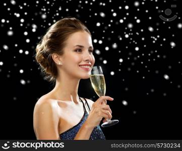 people, holidays, luxury and celebration concept - smiling woman holding glass of sparkling wine over black snowy background