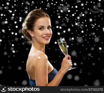 people, holidays, luxury and celebration concept - smiling woman holding glass of sparkling wine over black snowy background