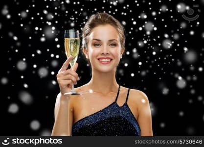 people, holidays, luxury and celebration concept - smiling woman holding glass of sparkling wine over black snowy background