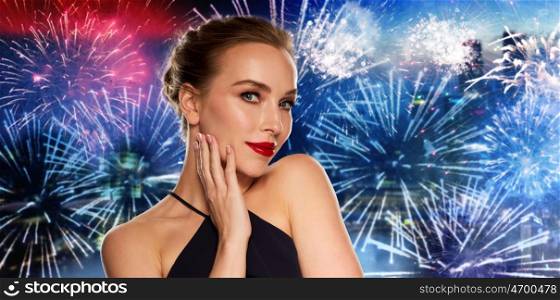 people, holidays, luxury and fashion concept - beautiful woman in black with red lips over night city firework background