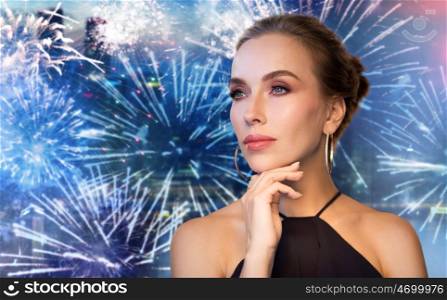 people, holidays, luxury, jewelry and fashion concept - beautiful woman in black wearing diamond earring and ring over night city firework background