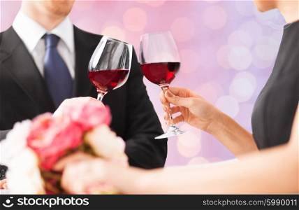 people, holidays, marriage and celebration concept - happy engaged with flowers clinking wine glasses over holidays lights background