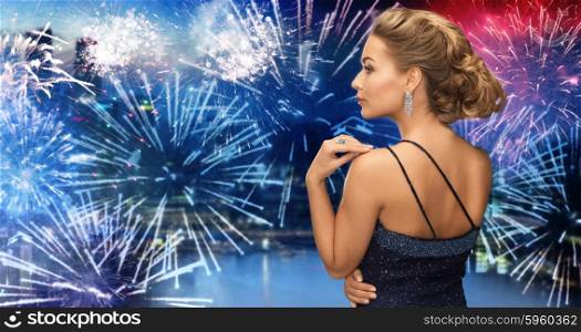 people, holidays, party, jewelry and glamour concept - beautiful woman with diamond earring over firework lights in city background