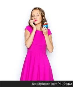 people, holidays, party, junk food and celebration concept - happy young woman or teen girl in pink dress with birthday cupcake