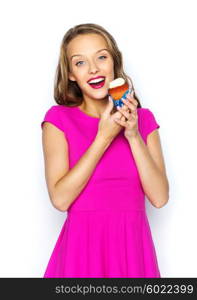 people, holidays, party, junk food and celebration concept - happy young woman or teen girl in pink dress with birthday cupcake