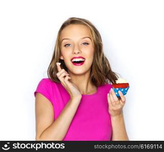 people, holidays, party, junk food and celebration concept - happy young woman or teen girl in pink dress with birthday cupcake