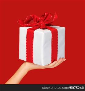 people, holidays, present, surprise and birthday concept - close up hand holding christmas gift box over red background