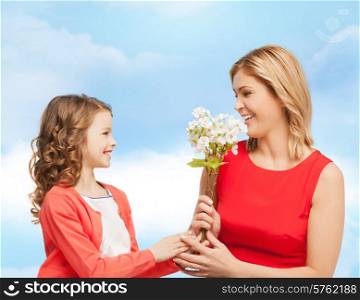 people, holidays, relations and family concept - happy little daughter giving flowers to her mother over blue sky background