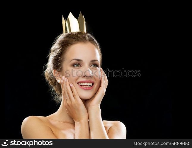 people, holidays, royalty and glamour concept - laughing woman wearing golden crown over black background