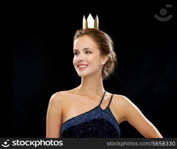 people, holidays, royalty and glamour concept - smiling woman in evening dress wearing golden crown over black background