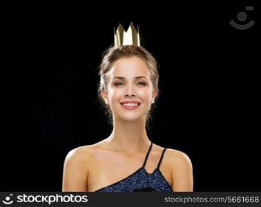people, holidays, royalty and glamour concept - smiling woman in evening dress wearing golden crown over black background