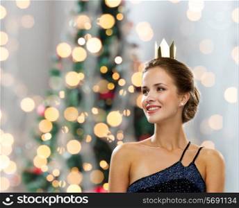 people, holidays, royalty and glamour concept - smiling woman in evening dress wearing golden crown over christmas tree lights background